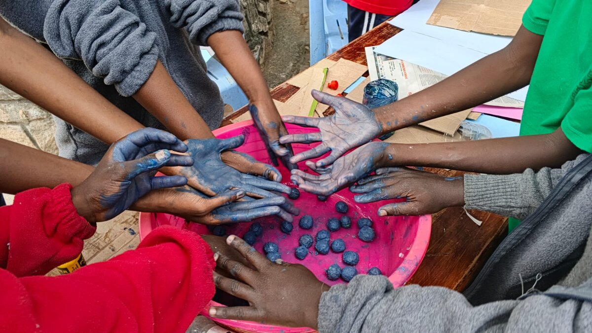 Learners' hands mixing blue paint during a hands-on art activity
